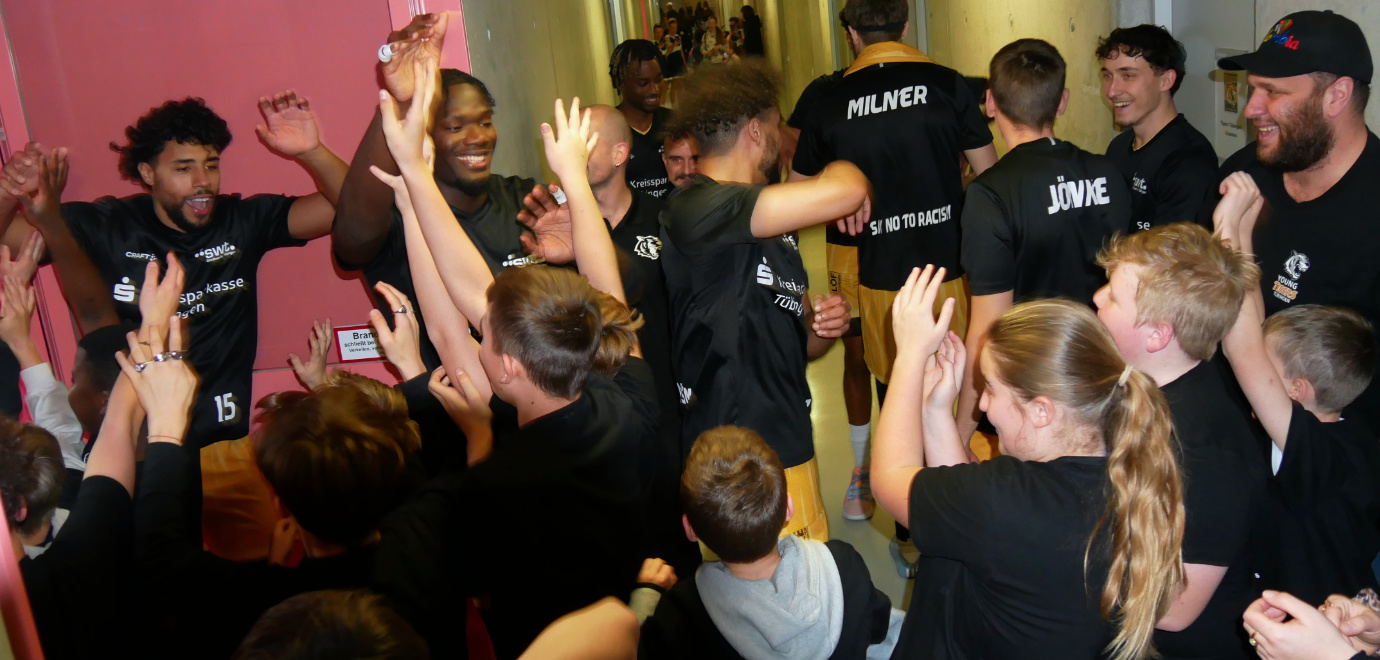 Schülerinnen und Schüler jubeln zusammen mit den Basketballspielern der Tigers Tübingen